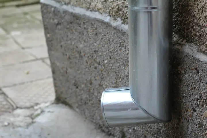 Downpipe outlet discharging at the base of a wall