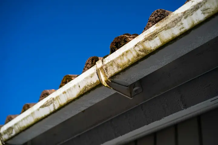 Worn UPVC gutter run held by a bracket along a roof edge